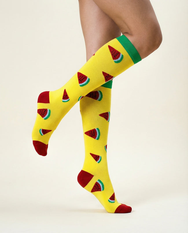 Yellow knee-high socks with watermelon pattern worn by a person on a beige background