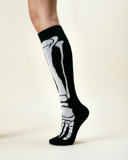 Knee-high black socks with white skeleton design worn by a person on a light background