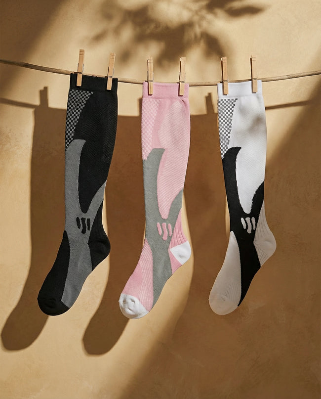 Three pairs of socks hanging on a line against a beige background