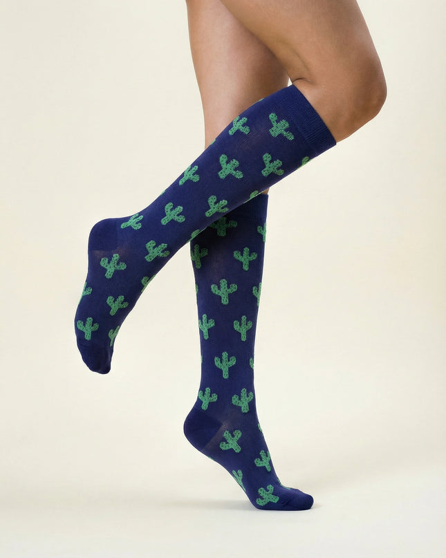 Navy blue knee-high socks with green cactus pattern worn by a person on a beige background