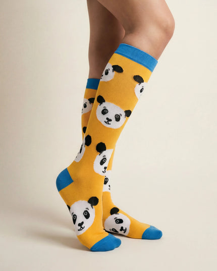 Yellow socks with panda pattern and blue toes worn by a person on a beige background