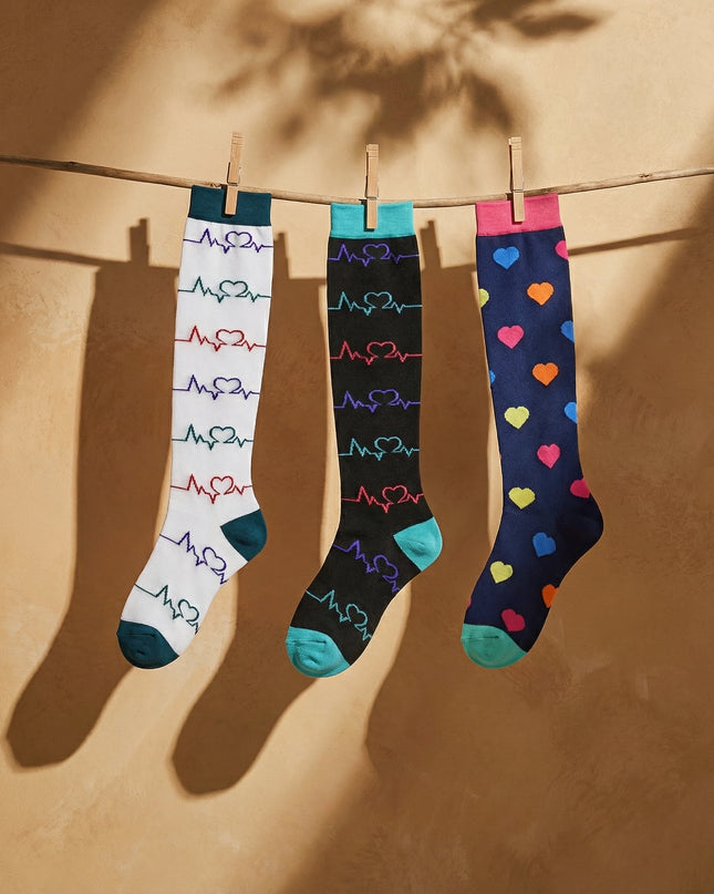 Three pairs of colorful socks hanging on a line against a beige wall.