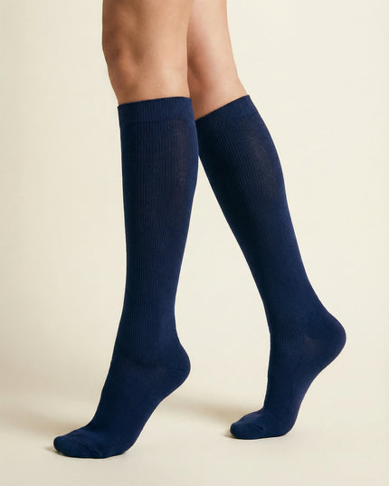 Navy blue knee-high socks worn by a person on a beige background