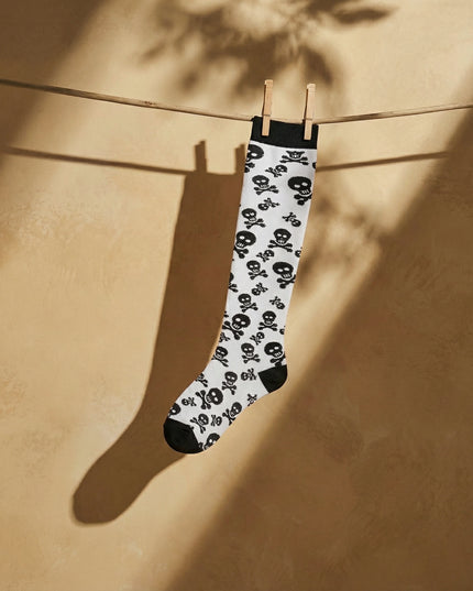 Skull-patterned sock hanging on a clothesline against a beige wall.