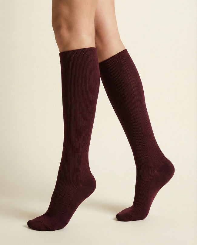 Maroon knee-high socks worn by a person on a beige background