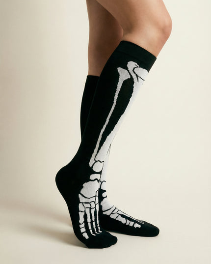 Black socks with white skeleton design worn by a person on a beige background
