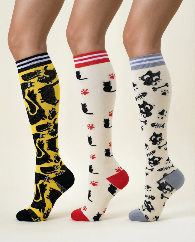 Three pairs of knee-high socks with cat patterns on a neutral background