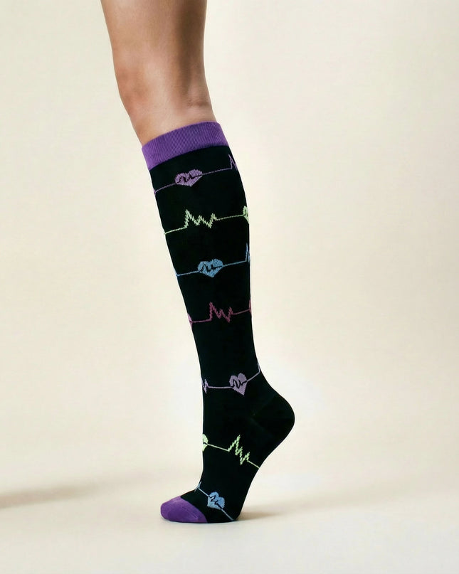 Black knee-high socks with colorful heart designs on a beige background