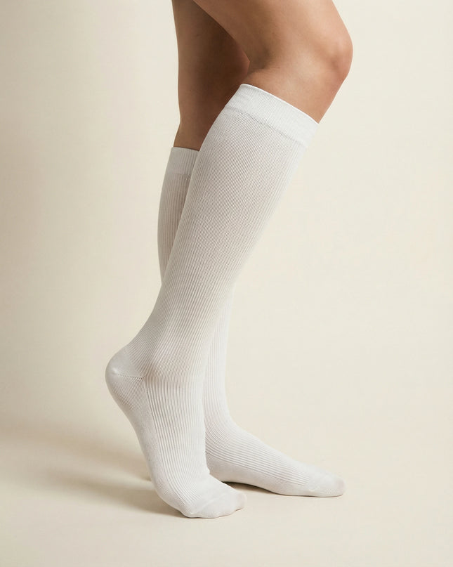 White knee-high socks worn by a person on a beige background