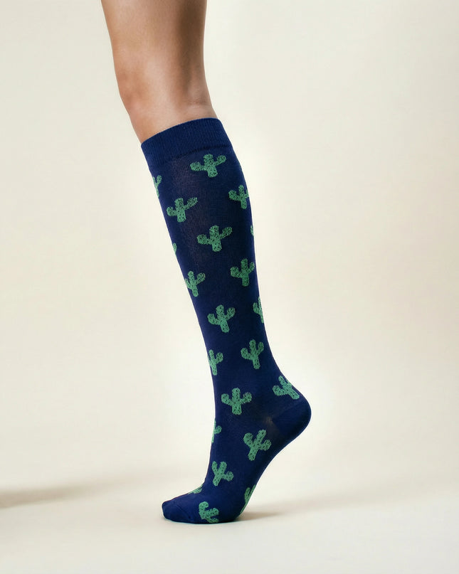 Navy blue knee-high socks with green cactus patterns on a beige background