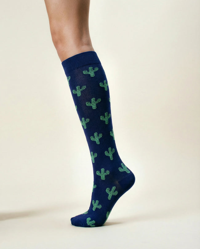 Navy blue knee-high socks with green cactus patterns on a beige background