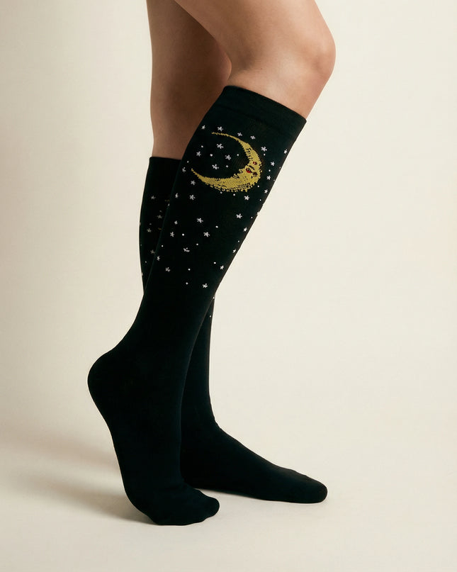 Black knee-high socks with celestial design worn by a person on a beige background