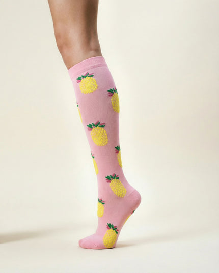 Pink knee-high socks with pineapple pattern worn by a person on a light beige background