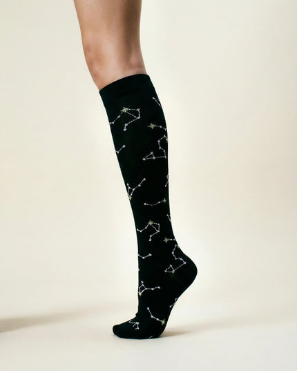 Black knee-high socks with white constellation patterns on a neutral background