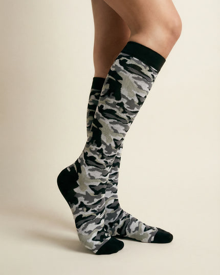Camouflage knee-high socks worn by a person on a beige background