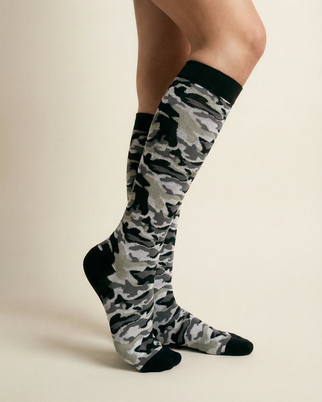 Camouflage knee-high socks worn by a person on a beige background