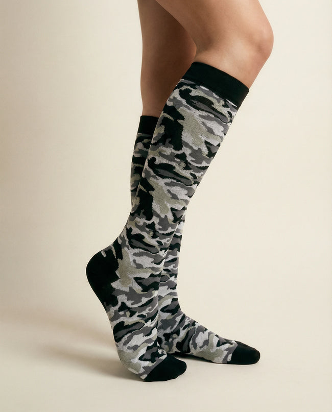 Camouflage knee-high socks worn by a person on a beige background