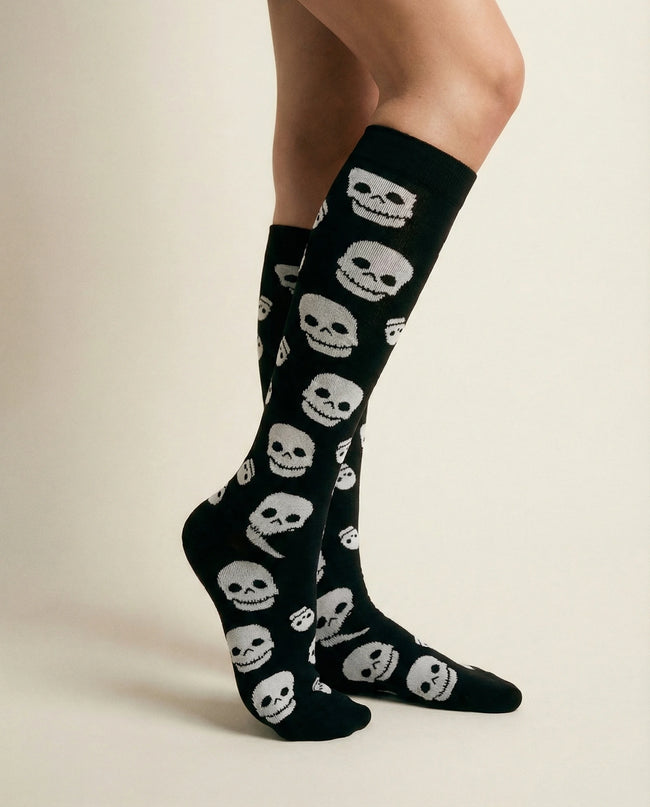 Black socks with white skull patterns worn by a person on a beige background