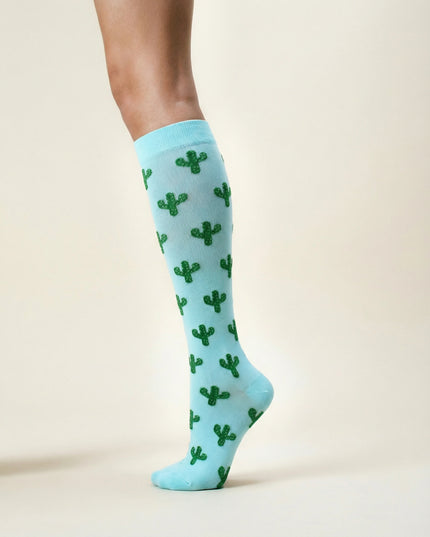Light blue knee-high socks with green cactus pattern worn by a person on a beige background