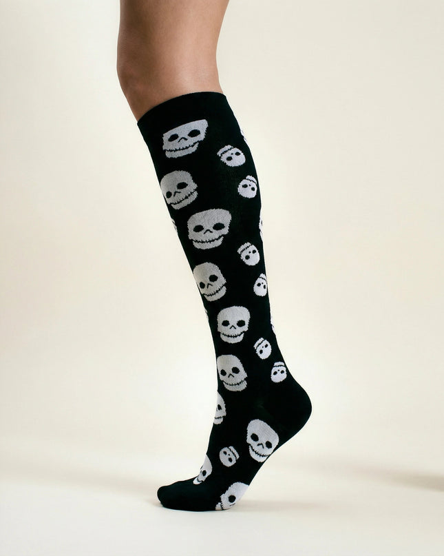 Black knee-high socks with white skull patterns on a neutral background